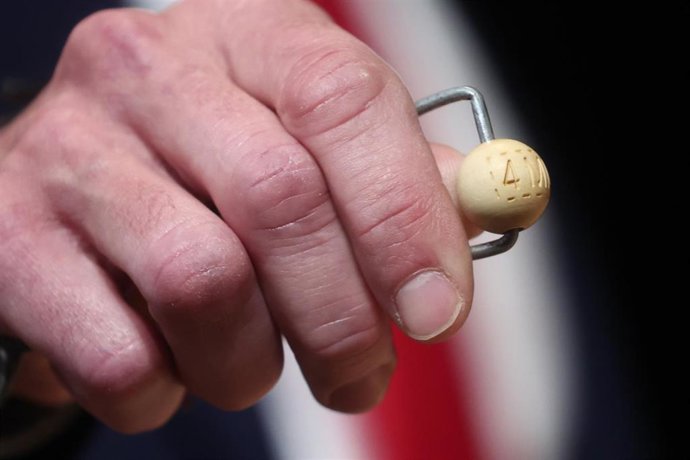 Un hombre mete las bolas con los premios en el bombo de la lotería durante la celebración del Sorteo Extraordinario de la Lotería de Navidad 2025, en el Teatro Real, a 22 de diciembre de 2025, en Madrid