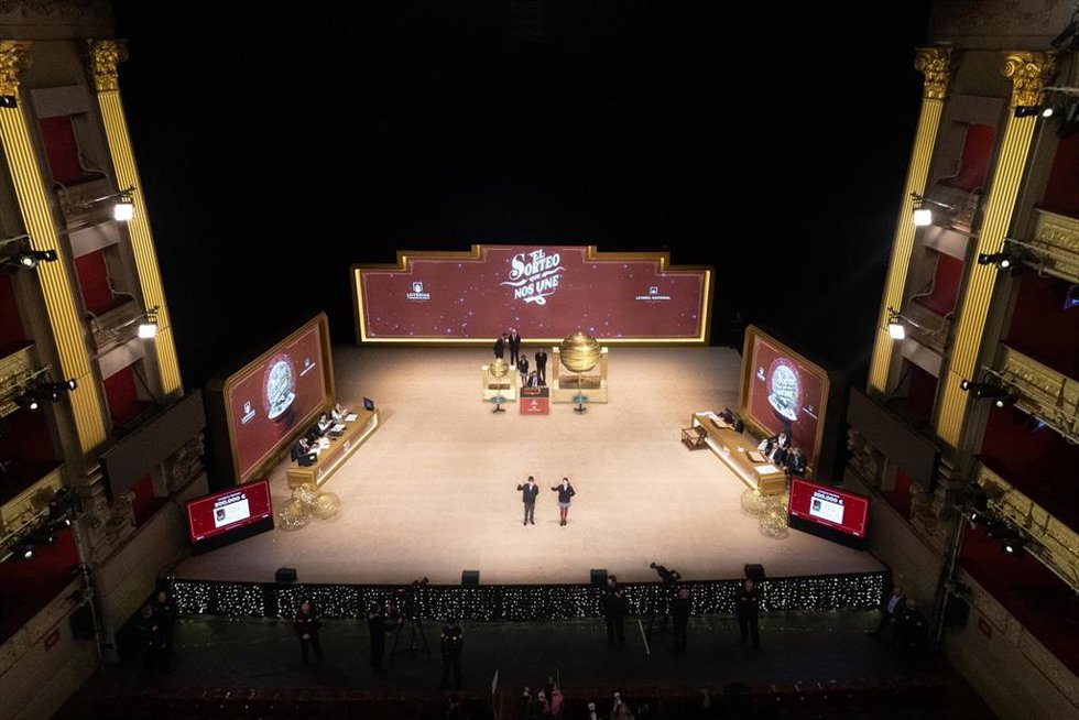 Varias personas ven como los niños del Colegio de San Idefonso cantan los números premiados durante la celebración del Sorteo Extraordinario de la Lotería de Navidad 2025, en el Teatro Real, a 22 de diciembre de 2025, en Madrid (España).