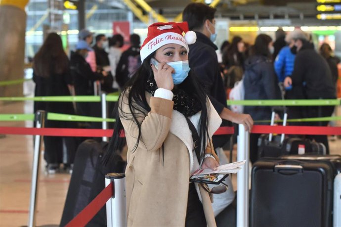 Archivo - Una mujer con un gorro de Papa Noel en  un aeropuerto.