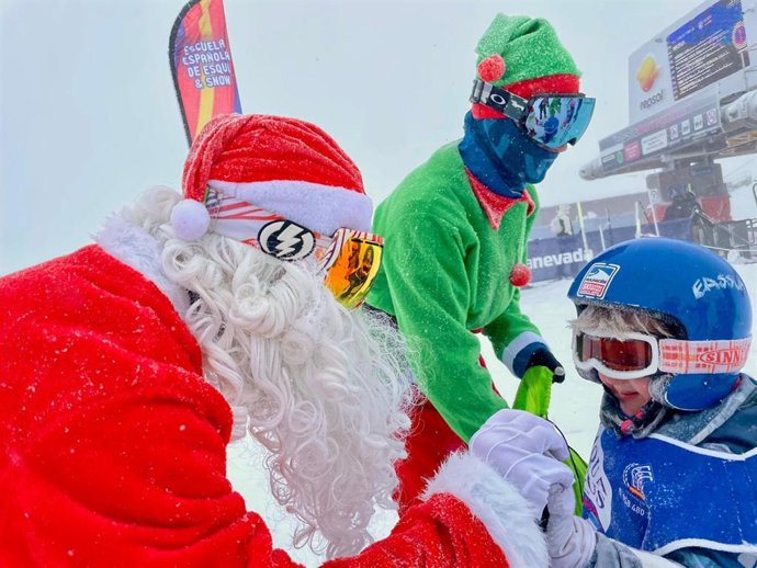 Papá Noel saluda a un joven usuario de la estación de esquí de Sierra Nevada, en Monachil (Granada)