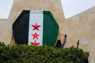 Archivo - Nueva bandera siria pintada sobre la fachada de un edificio en Hama, en el oeste de Siria