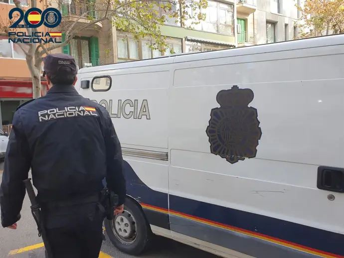 Un agente de la Policía Nacional, de espaldas y junto a un furgón.