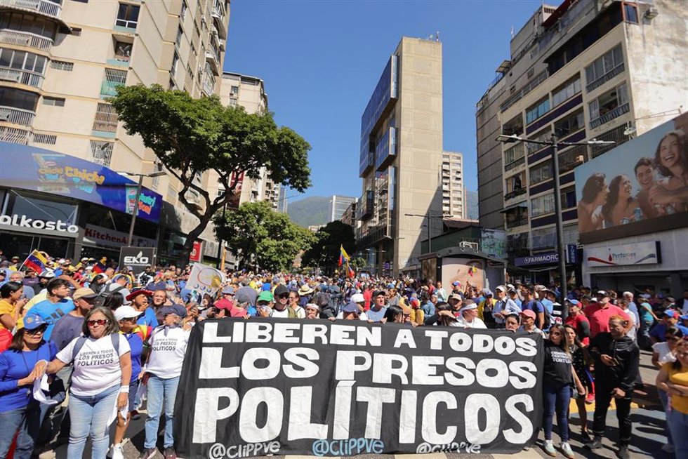 Archivo - Opositores al Gobierno de Nicolás Maduro sostienen una pancarta con la leyenda "Liberen a todos los presos políticos" durante una manifestación convocada un día antes de la investidura del presidente