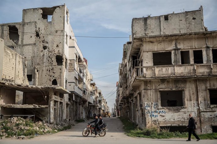 Archivo - Arquivo - 26 de março de 2025, Homs, Síria: Homens em uma motocicleta em um bairro danificado em Homs. Homs, a terceira maior cidade da Síria, já foi conhecida como a "capital" da revolução.