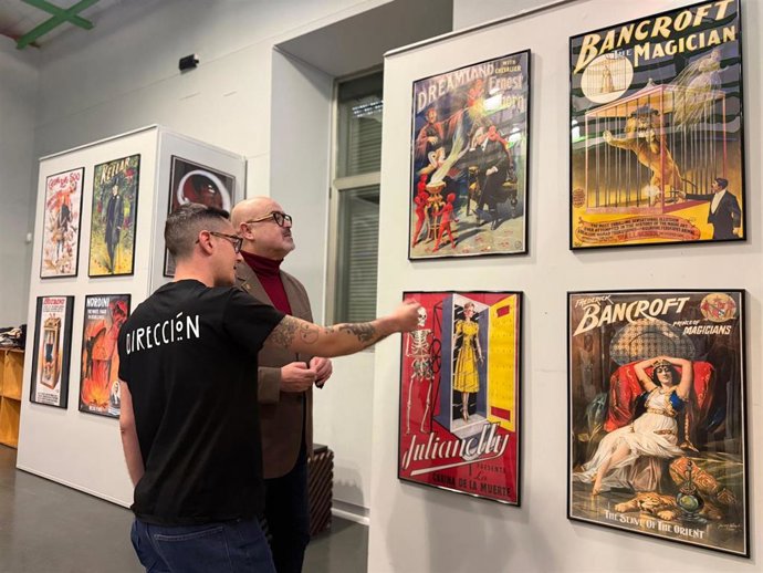 El mago y organizador de la muestra, Iván Asenjo (de espaldas), comenta con el concejal de Cultura, Juan Carlos Monroy, algunos carteles de la exposición.