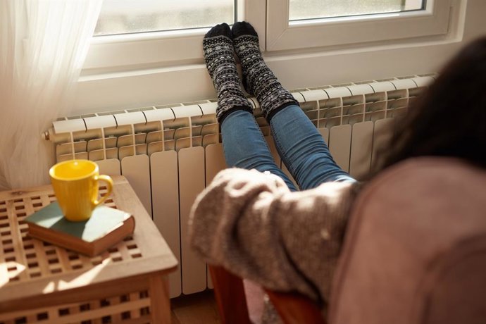 Archivo - Mujer calentando los pies en un frío día de invierno.