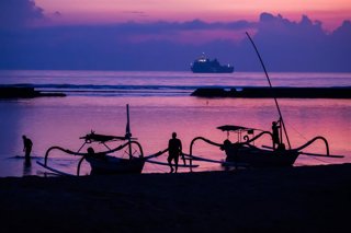 Archivo - FILED - 14 November 2022, Indonesia, Nusa Dua: Men attach boats to the beach of Nusa Dua before sunrise on the day before the start of the G20 summit, with an Indonesian Navy ship visible in the background. Starting next year, tourists entering 