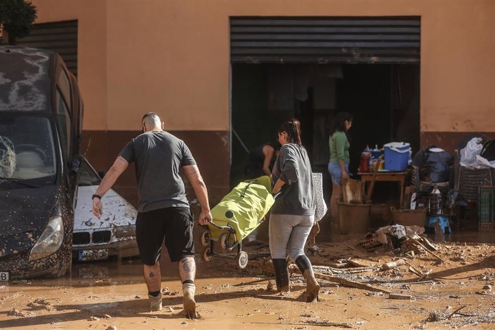Archivo - Varias personas limpian los destrozos tras el paso de la DANA en el barrio de la Torre, en Valncia. ARCHIVO. 