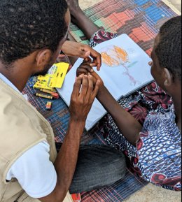 Santina, 13, draws a picture in the Rhino Refugee Settlement in Uganda.  HI