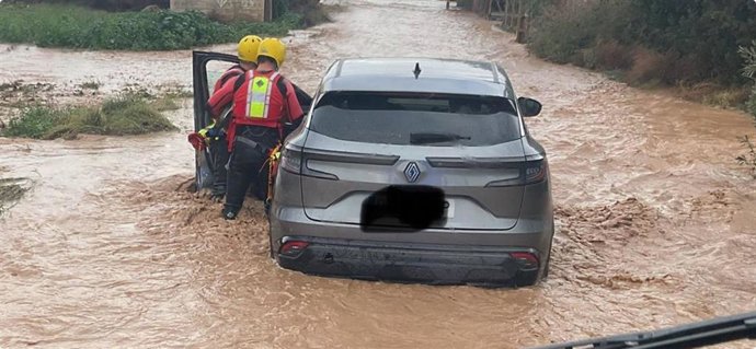 Bomberos rescatando a la persona atrapada en su vehículo.