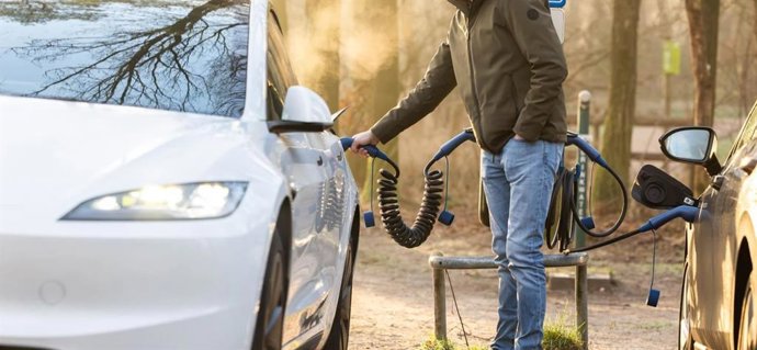 Un conductor recarga un coche eléctrico