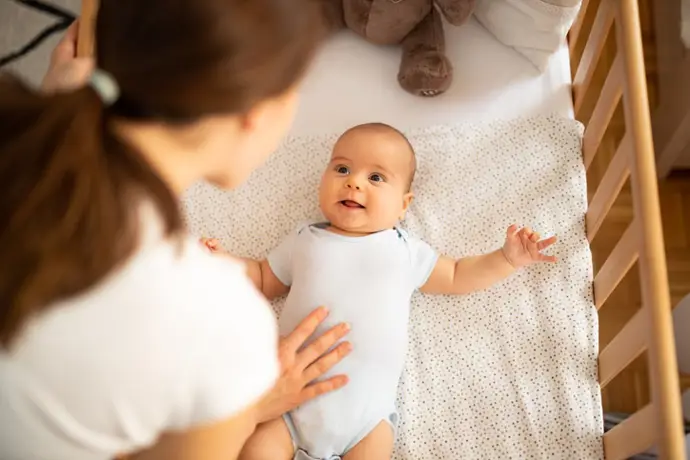 Madre mirando a su bebé en la cuna