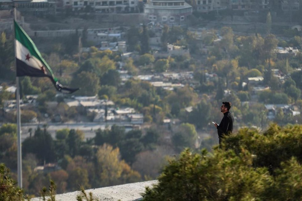 Un hombre cerca de una bandera de Siria en la capital, Damasco (archivo)