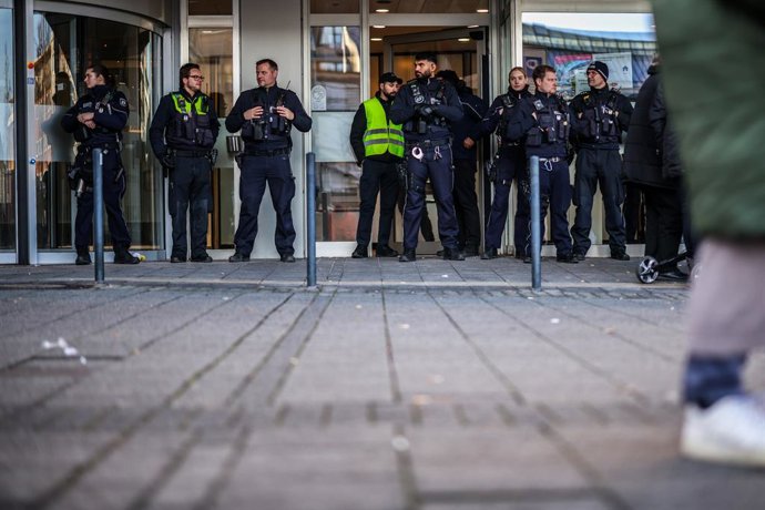 30 December 2025, North Rhine-Westphalia, Gelsenkirchen: Police officers stand in front of the savings bank branch in the Buer district. After the break-in into the bank's vault, worried customers are demanding information. Due to the situation, the branc