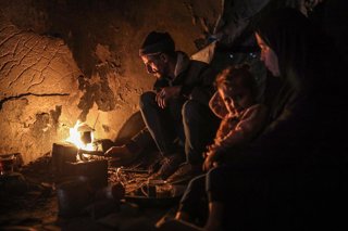 Familias palestinas se reúnen alrededor de una fogata en Gaza