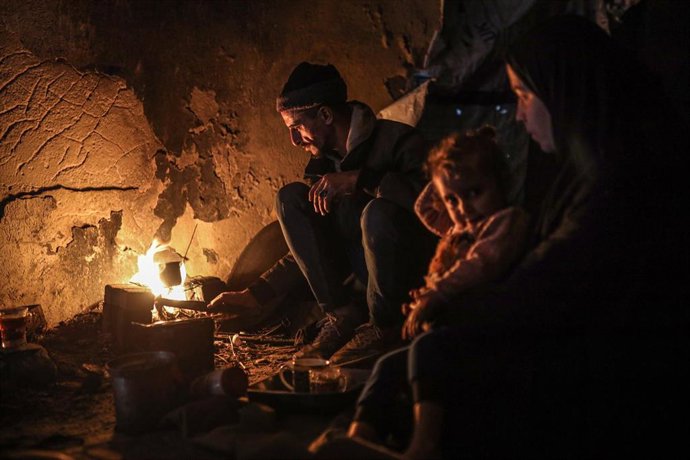 Familias palestinas se reúnen alrededor de una fogata en Gaza