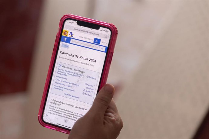 Archivo - Una persona cumplimenta la Declaración de la Renta con su teléfono móvil.