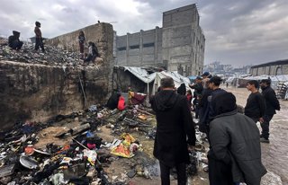 Palestinos inspeccionan los restos de una tienda de campaña incendiada en el campamento de refugiados de Yarmuk, en la ciudad de Gaza, un suceso que se saldó con la muerte de dos personas