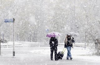 Archivo - Paseantes cubiertos de nieve el pasado mes de noviembre en Vitoria.