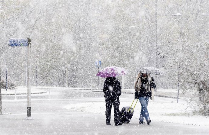 Archivo - Paseantes cubiertos de nieve el pasado mes de noviembre en Vitoria.
