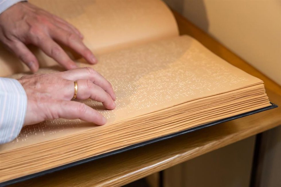 Archivo - Una mujer leyendo un libro en braille.