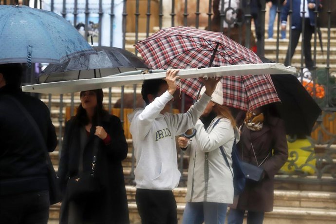 Archivo - Imagen de archivo de varias personas resguardándose de la lluvia en Málaga.