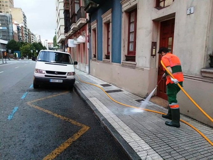 Archivo - Operario de Emulsa realiza un baldeo de una acera en Gijón.