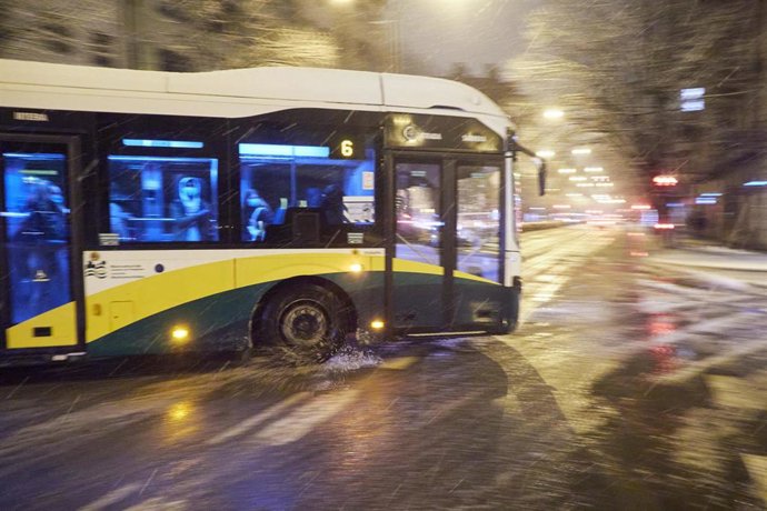 Archivo - Un autobús circula por una calle nevada, en una imagen de archivo