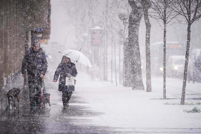 Archivo - Dos personas caminan por una de las calles de Vitoria-Gasteiz durante una nevada (archivo)