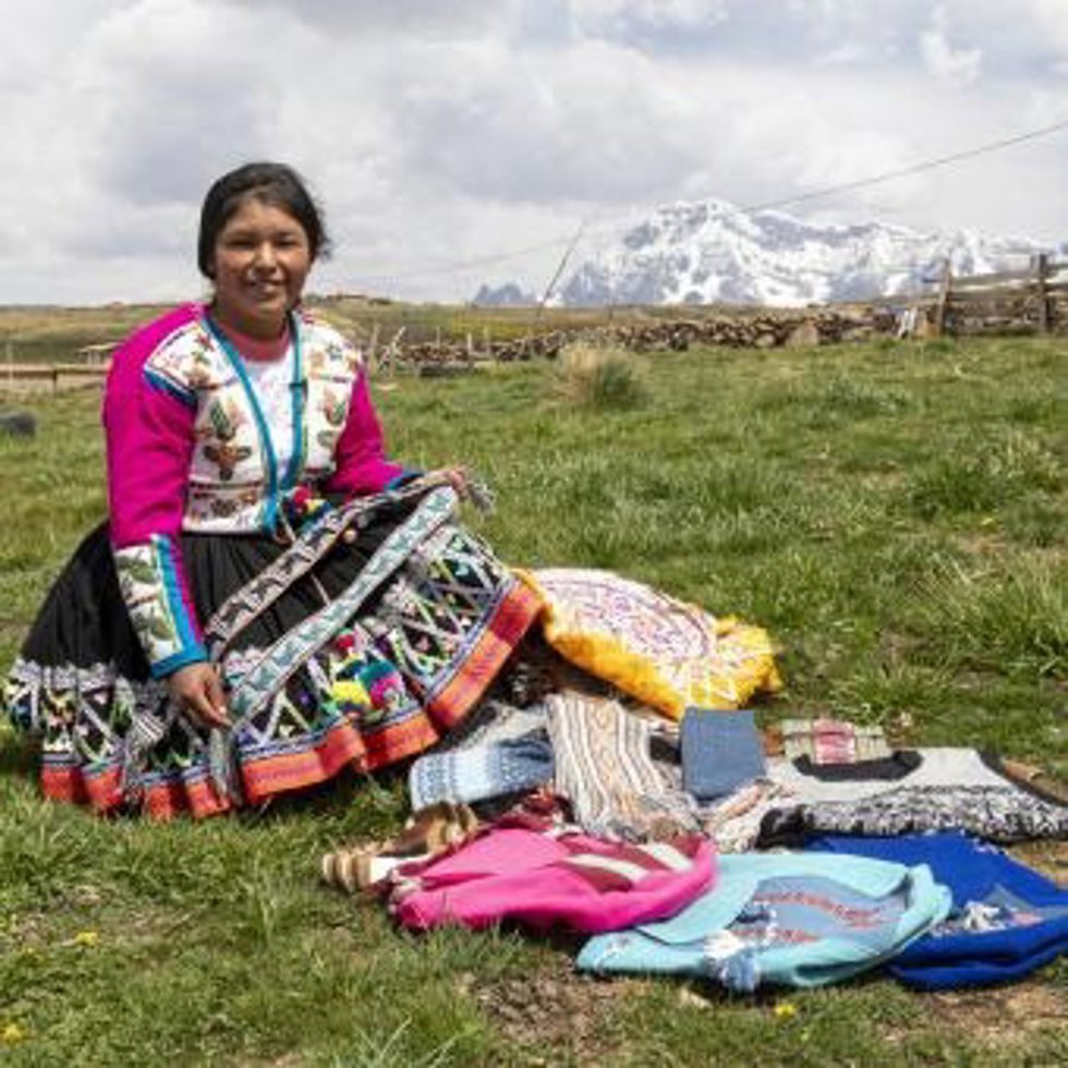 Marleny, lideresa de la organización ATIPTALLA, muestra con orgullo los tejidos y prendas elaboradas con lana de alpaca, que son ofrecidos a los visitantes.