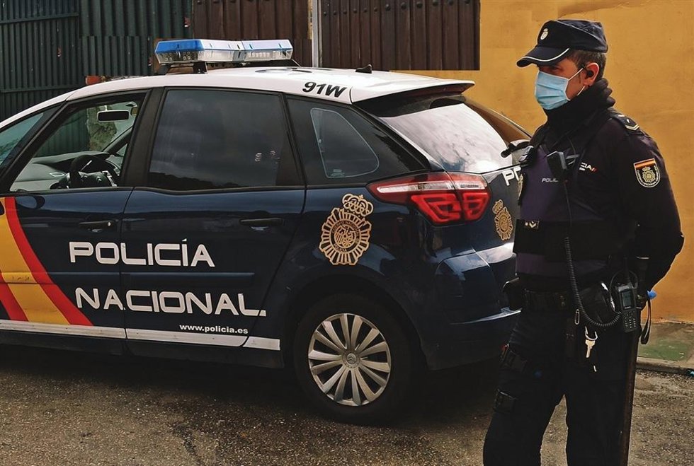 Archivo - Imagen de archivo de un ehículo y un agente de la Policía Nacional.