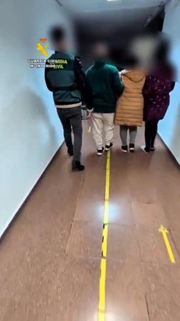 UN agente conduce a varios de los detenidos.