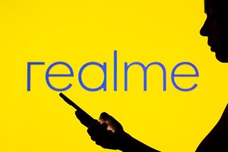 Archivo - May 2, 2022, Brazil: In this photo illustration, the Realme logo is seen in the background of a silhouetted woman holding a mobile phone.