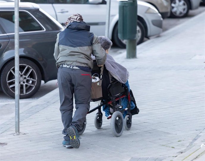 Archivo - Una persona empuja una silla de ruedas.