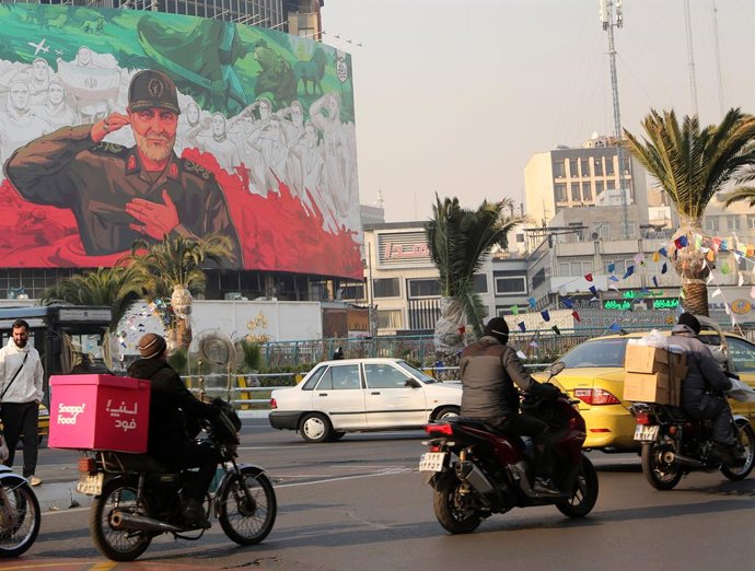 TEERÃ, 7 de janeiro de 2026 — Pessoas passam de carro por um outdoor com a imagem de Qassem Soleimani, ex-comandante da Força Quds do Corpo da Guarda Revolucionária Islâmica (IRGC), no centro de Teerã, Irã, em 6 de janeiro de 2026. O chefe do exército ira