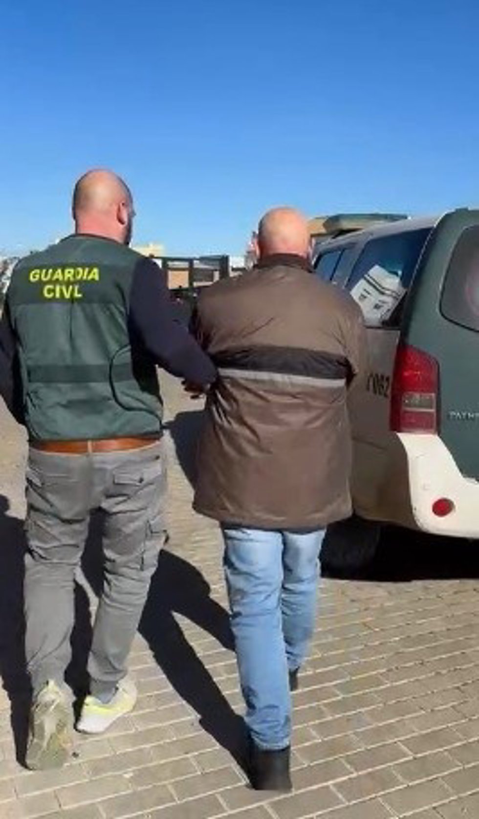 Un agente traslada hasta un vehículo de la Guardia Civil al detenido como presunto autor de una mujer en Olvera.