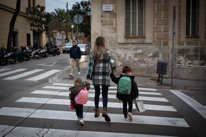 Archivo - Dos niñas de la mano con una mujer a su llegada al primer día de clase, en una imagen de archivo