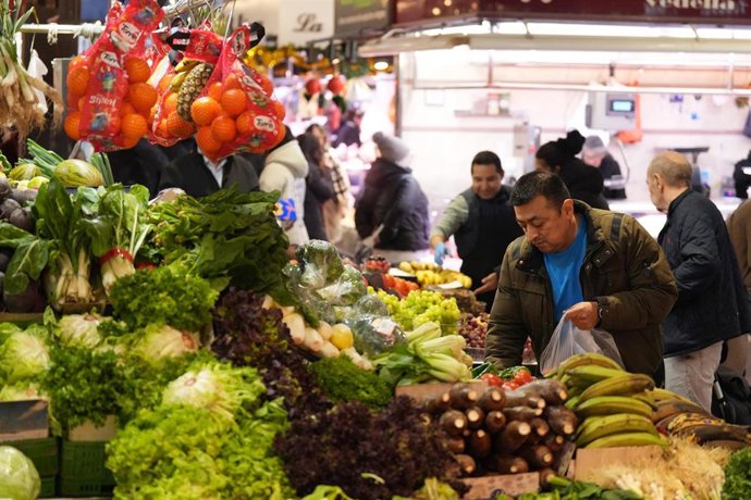 Varias personas compran en un mercado municipal.