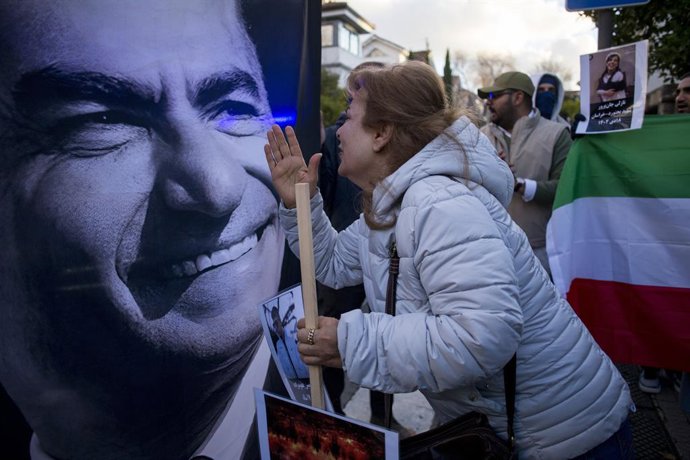 14 de janeiro de 2026, Madri, Madri, Espanha: Uma mulher da comunidade iraniana em Madri se aproxima para tocar uma faixa com o rosto de Mohammad Reza Pahlavi, imperador do Irã, durante um protesto em frente à Embaixada do Irã em Madri. Os manifestantes e