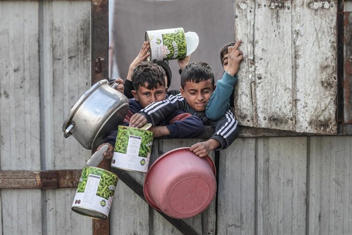 10 de janeiro de 2026, Nusairat, Faixa de Gaza, Território Palestino: Crianças palestinas aguardam para receber refeições quentes, distribuídas por uma organização de caridade, enquanto a crise alimentar continua devido à ajuda humanitária limitada no Cam