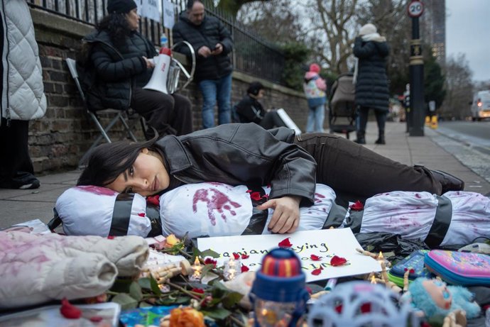 14 de janeiro de 2026, Londres, Reino Unido: Um manifestante abraça um cadáver humano envolto em um lençol, simbolizando uma vítima morta pelo regime iraniano. Centenas de monarquistas iranianos se reuniram em frente à Embaixada do Irã em Londres, Reino U