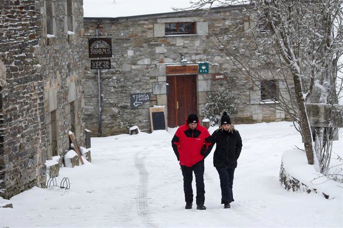 Archivo - Dos personas caminan sobre la nieve en Pedrafia do Cebreiro, Lugo (Galicia).
