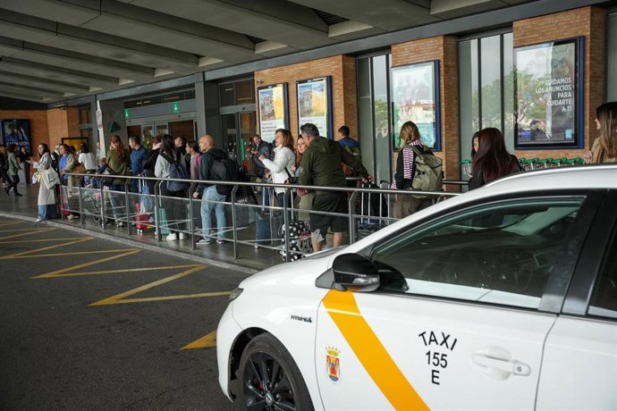 Archivo - Un taxi está estacionado en la parada de la estación de trenes de Santa Justa, con pasajeros que guardan cola al foto, en una imagen de recurso. 