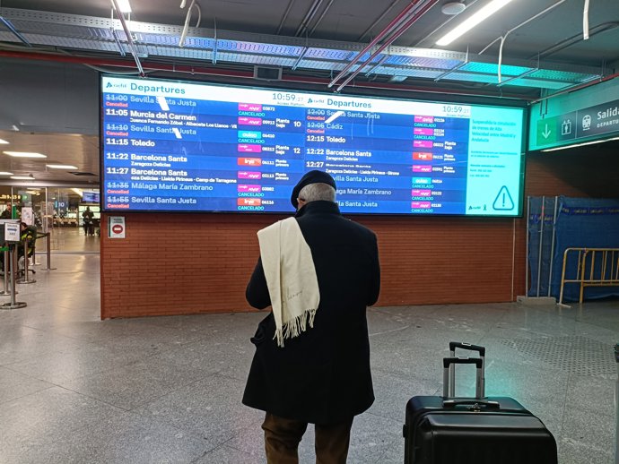Un viajero mira la pantalla en la que aparecen varios trenes cancelados a Andalucía, en la estación Puerta de Atocha-Almudena Grandes.