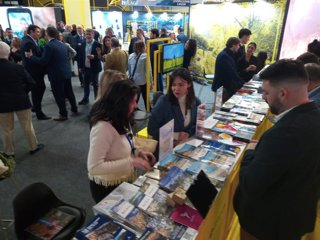Archivo - Varias personas recogen folletos con destinos turísticos del pabellón de la Diputación de Sevilla en Fitur.
