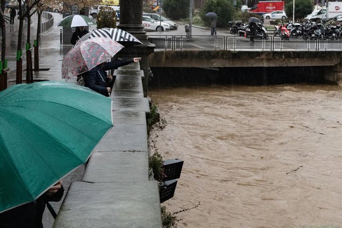 Varias personas observan la crecida del río Onyar, a su paso por el centro de la ciudad, a 20 de enero de 2026, en Girona, Catalunya (España).