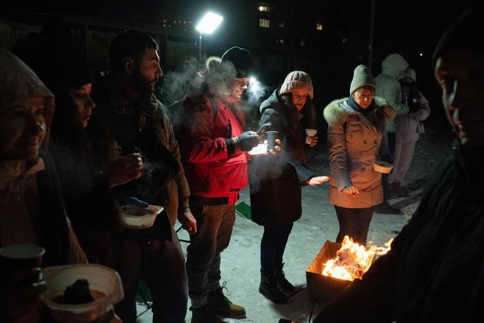 18 de janeiro de 2026, Kiev, Ucrânia: Moradores de um prédio de apartamentos no bairro de Pozniaky grelham carne em churrasqueiras no pátio à luz de lanternas durante prolongadas quedas de energia e interrupções no aquecimento causadas por ataques com mís