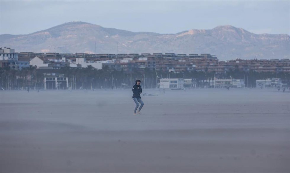 Archivo - Una mujer camina por la playa mientras le da el viento, en Valencia. 