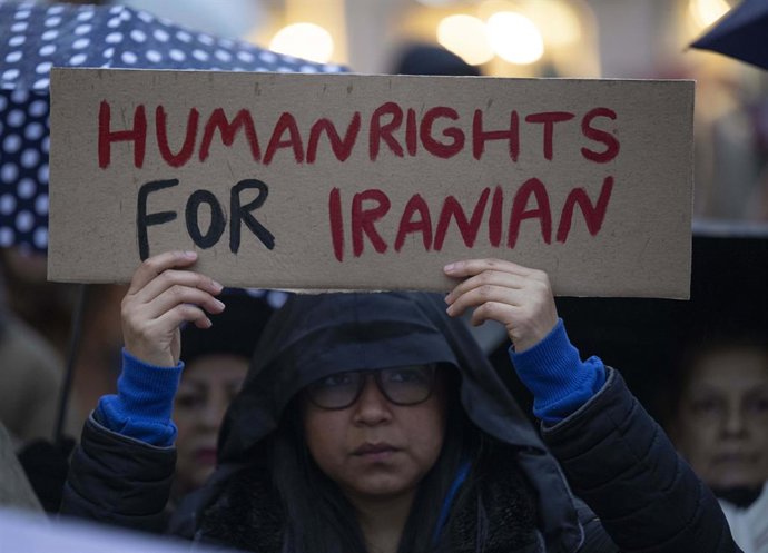 12 January 2026, Hesse, Frankfurt_Main: A participant holds a banner reading "Human Rights for Iranian" during a rally in Frankfurt to demonstrate against the regime in Iran. Photo: Boris Roessler/dpa