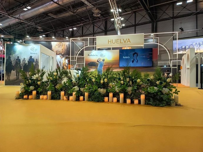 El stand de Huelva en Fitur con un altar de flores y velas.